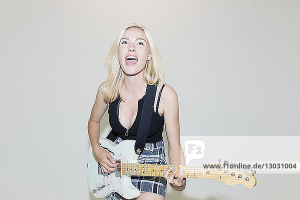 Exuberant young woman playing electric guitar