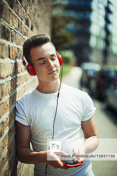Gelassene junge Frau  die mit Kopfhörern und mp3-Player Musik hört