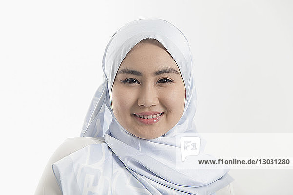 Porträt einer lächelnden  selbstbewussten jungen Frau  die einen blauen Hidschab aus Seide trägt
