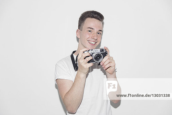 Porträt lächelnder  selbstbewusster Jugendlicher mit Retro-Kamera
