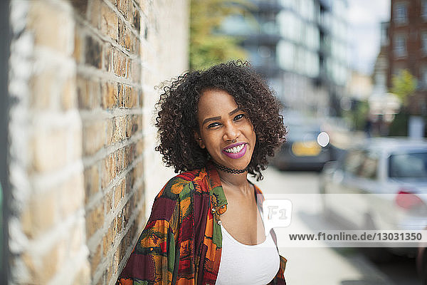 Porträt einer glücklichen  selbstbewussten jungen Frau auf einem Bürgersteig in der Stadt