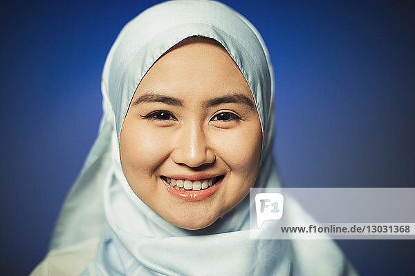 Nahaufnahme eines Porträts einer lächelnden  selbstbewussten jungen Frau  die einen blauen Hidschab aus Seide trägt