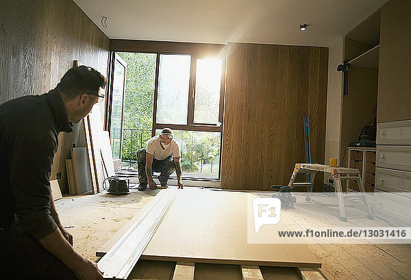 Bauarbeiter messen Holzplatten im Haus aus