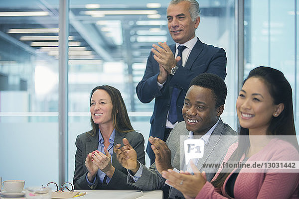 Business people smiling and clapping in conference room meeting