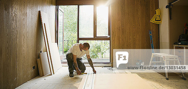 Bauarbeiter beim Messen von Holzplatten in einem Haus