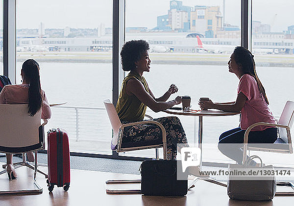Businesswomen talking and drinking coffee in airport business lounge
