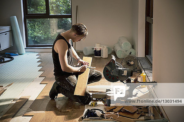 Construction worker preparing hardwood flooring in house