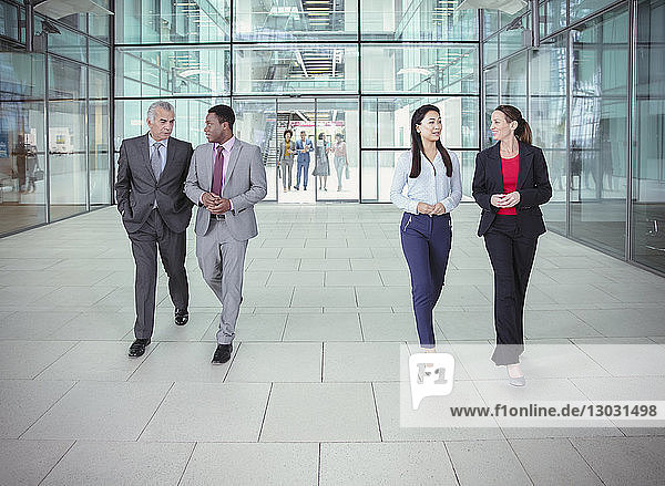Business people walking and talking outside modern office building