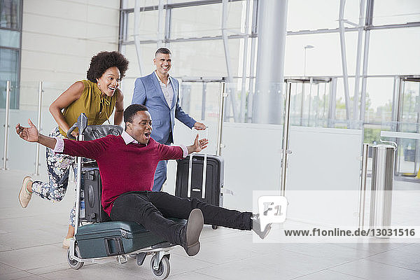 Verspieltes Paar läuft mit Gepäckwagen im Flughafen
