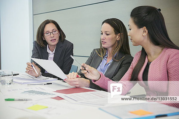Businesswomen discussing paperwork in conference room meeting