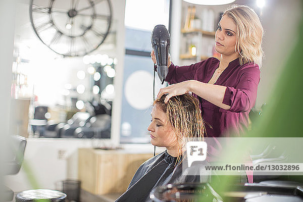 Hairdresser blow drying customer's hair in salon