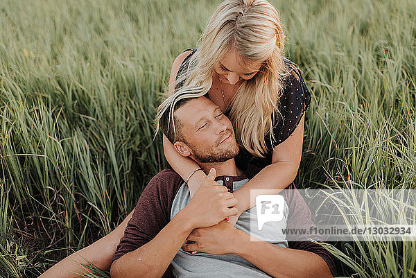 Romantic young woman and boyfriend reclining together in field of long grass