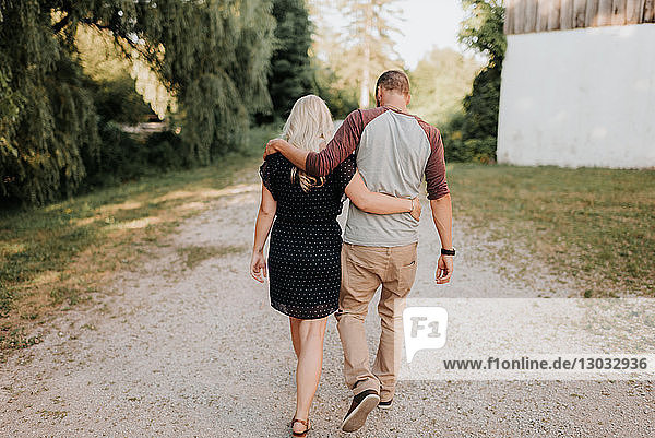 Romantischer Mann und Freundin schlendern Hand in Hand auf ländlichem Feldweg  Rückansicht