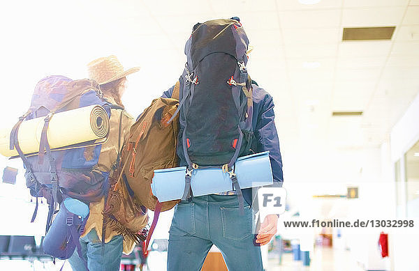 Junges Paar am Flughafen  Rucksäcke tragend  Rückansicht