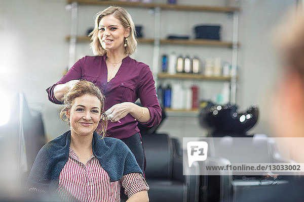 Friseur frisiert die Haare des Kunden im Salon