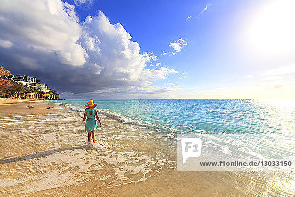 Rückansicht einer Frau mit Hut  die am Ffryes Beach spazieren geht  Antigua  Antigua und Barbuda  Leeward Islands  Westindien  Karibik