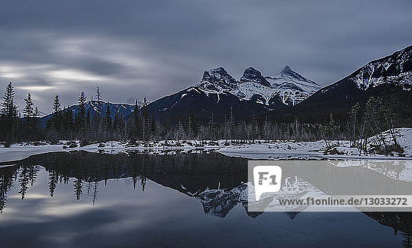 Canadian Rockies on a gloomy day  showing The Three Sisters over lake reflection  Alberta  Canada