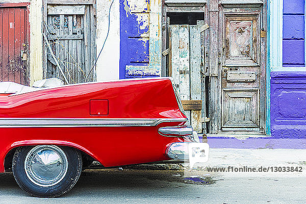 Ein roter Oldtimer  geparkt vor der farbenfrohen lokalen Architektur in Havanna  Kuba  Westindien  Karibik