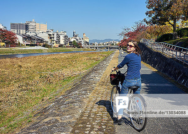 Cycling along the bank of the Kamo River in autumn  Kyoto  Japan