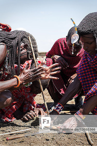 Masai-Männer beim Entzünden eines Feuers mit traditionellen Methoden  Masai Mara Dorf im Nationalreservat  Kenia  Ostafrika