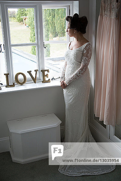 Braut schaut vor der Hochzeit aus dem Fenster