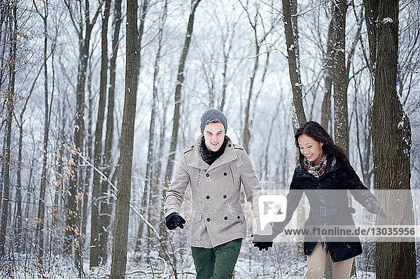 Young couple walking hand in hand in snow covered forest  Ontario  Canada