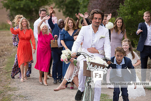 Hochzeitsgäste winken Brautpaare auf Fahrrädern ab