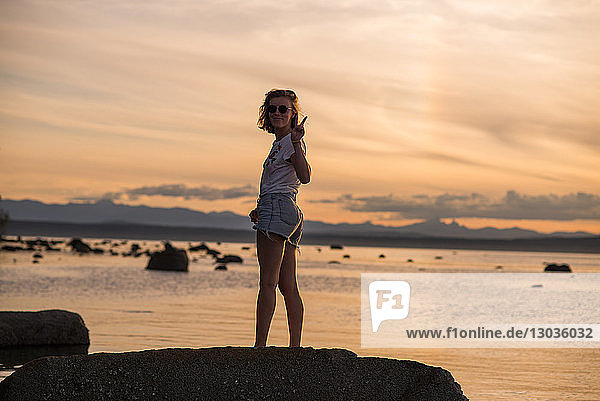 Junge Frau steht bei Sonnenuntergang auf einem Felsen  Porträt  Quadra Island  Campbell River  Kanada