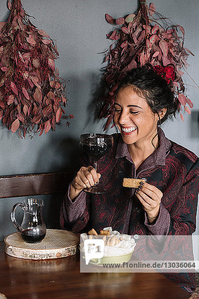 Young woman at rustic table holding glass of red wine