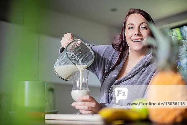 Woman having smoothie for breakfast at home