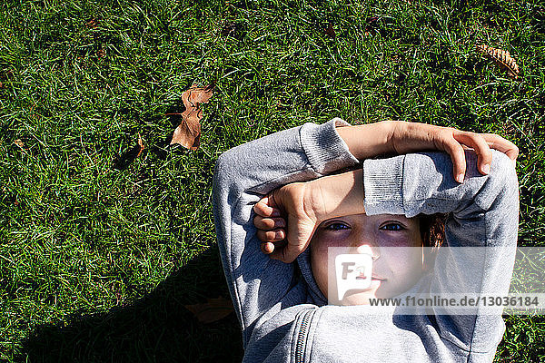 Junge auf Gras blockiert Sonnenlicht mit Armen