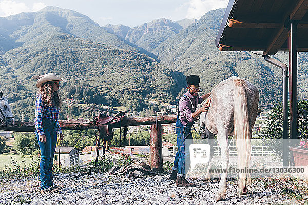 Junger Mann pflegt Pferd in ländlicher Reitarena  Primaluna  Trentino-Südtirol  Italien