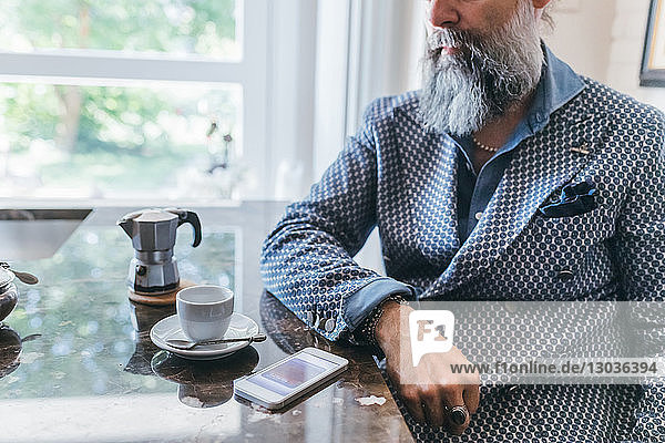 Mann benutzt Handy bei Kaffee in der Küche