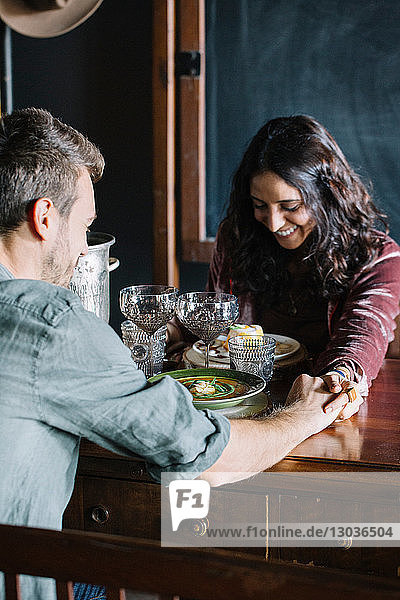Romantisches junges Paar beim Essen  Hände über den Tisch haltend
