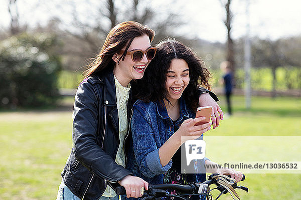 Teenager-Mädchen lesen gemeinsam Texte auf dem Fahrrad