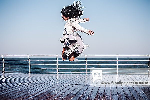 Mittlere erwachsene Frau springt mitten in der Luft auf dem Seepier  Odessa  Odeska Oblast  Ukraine