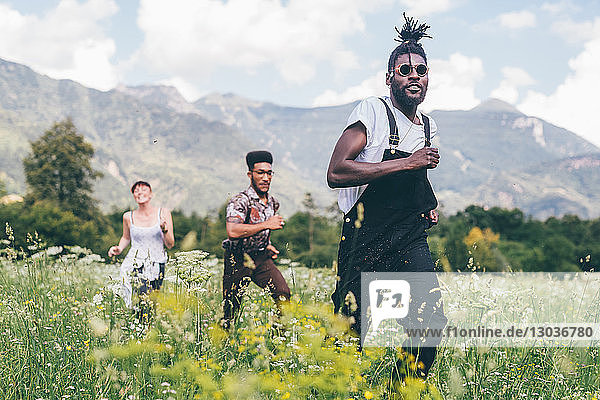 Three adult friends racing through wildflower meadow  Primaluna  Trentino-Alto Adige  Italy