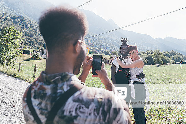 Junger Mann auf ländlichem Feldweg fotografiert Freunde auf Smartphone  Primaluna  Trentino-Südtirol  Italien