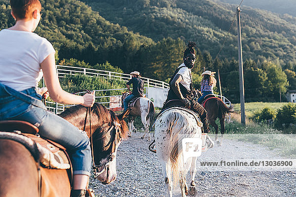 Erwachsene Freunde reiten auf Pferden auf ländlichem Feldweg  Rückansicht  Primaluna  Trentino-Südtirol  Italien