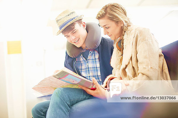 Junges Paar sitzt in der Abflughalle des Flughafens  schaut auf die Karte  plant die Reise  niedriger Blickwinkel