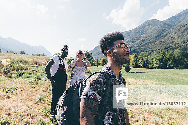 Drei junge Wanderfreunde blicken von der Feldlandschaft auf  Primaluna  Trentino-Südtirol  Italien