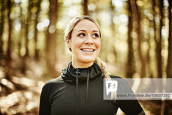 A head and shoulders portrait of a young blonde woman in sportswear in a forest