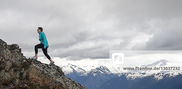 Side view shot of a mid adult woman hiking up rocky ridge in mountains  Whistler  British Columbia  Canada