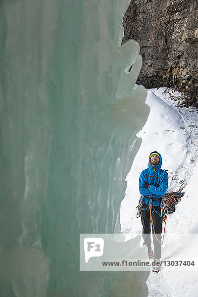 Eisblock vor einem männlichen Kletterer  der auf Schnee steht und nach oben schaut  bevor er im Rigid Designator Amphitheater  Vail  Colorado  USA  klettert