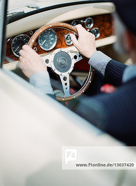 Over the shoulder shot of a man driving a luxury antique car