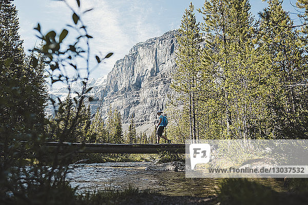 Wanderin beim Überqueren der Brücke über den Stanley Glacier River mit den Rocky Mountains im Hintergrund  British Columbia  Kanada