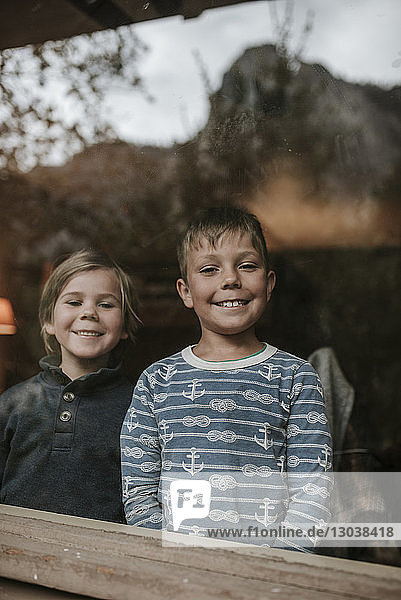 Portrait of cheerful brothers seen through window