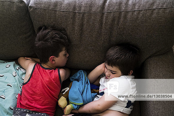High angle view of brothers sleeping on sofa at home