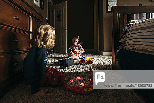Jungen  die mit Spielzeug spielen  während sie zu Hause auf dem Boden sitzen
