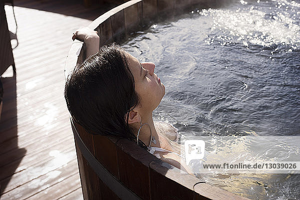 Frau entspannt sich an einem sonnigen Tag in einer Holzbadewanne